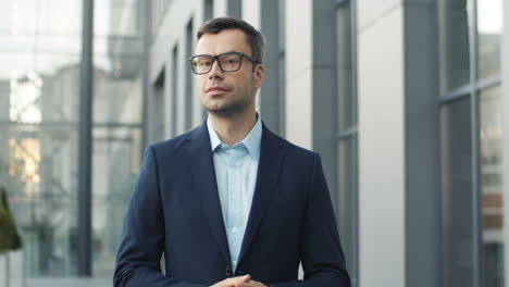 portrait of smiling businessman in glasses in the street and looking to the camera 1