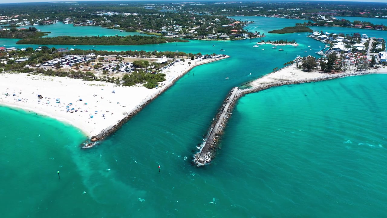 Un molo si estende in acque color acquamarina, separando spiagge sabbiose da corsi d'acqua interni. Perfetto per contenuti di viaggio o per servizi sullo sviluppo costiero