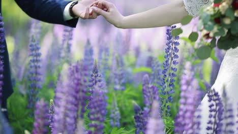 beautiful couple in flower field. happy loving couple holding hands in field of lupine