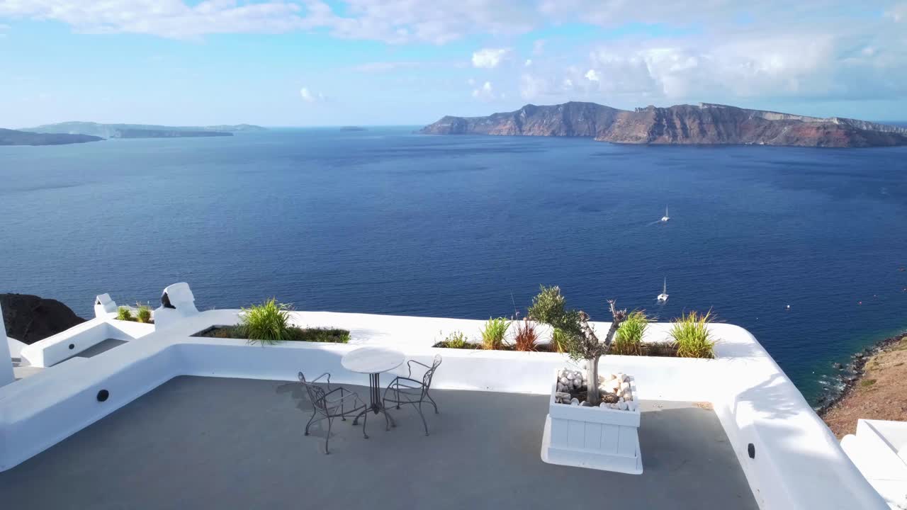 mesa con 2 sillas en una terraza en santorini, vista al volcán, mar egeo