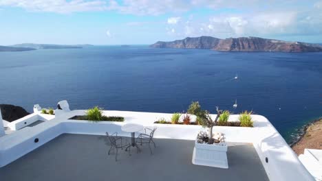 Mesa-Con-2-Sillas-En-Una-Terraza-En-Santorini,-Vista-Al-Volcán,-Mar-Egeo