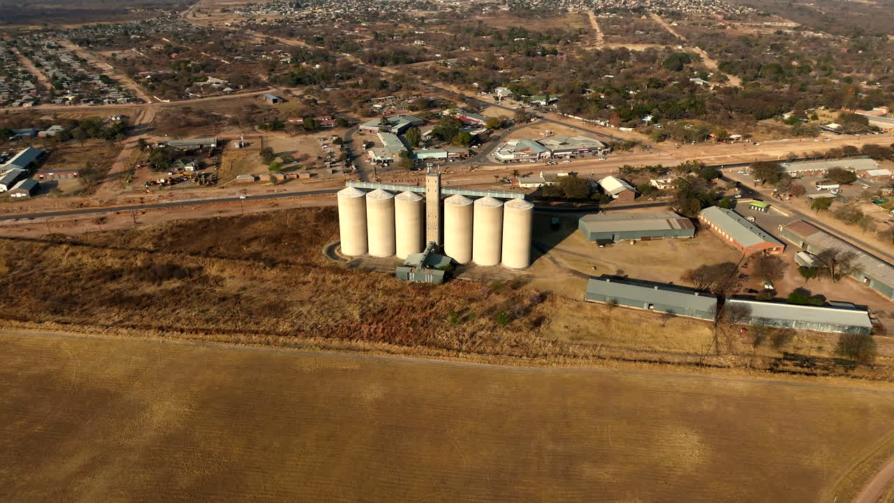 Zylindrische Turmsilos in der trockenen Landschaft von Vaalwater neben Ackerland.