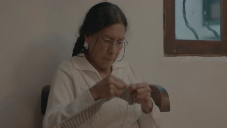 Toma-En-Cámara-Lenta-De-Una-Anciana-Abuela-Tejiendo-El-Patrón-En-Una-Bufanda-En-Casa