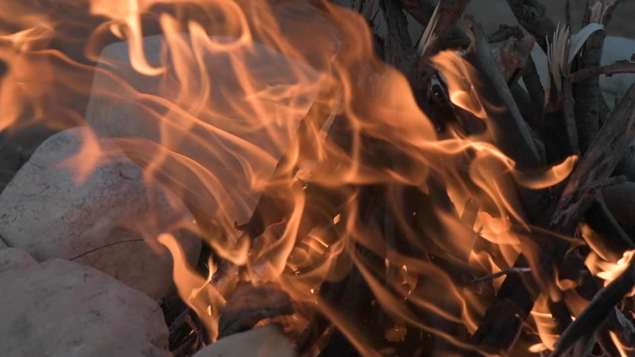 campfire made from wood and a surrounded by small rocks, shot with slow motion in a selective focus