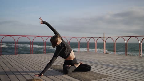 woman practicing yoga on a wooden pier overlooking the ocean