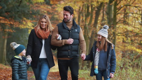 smiling family walking along path through autumn countryside together