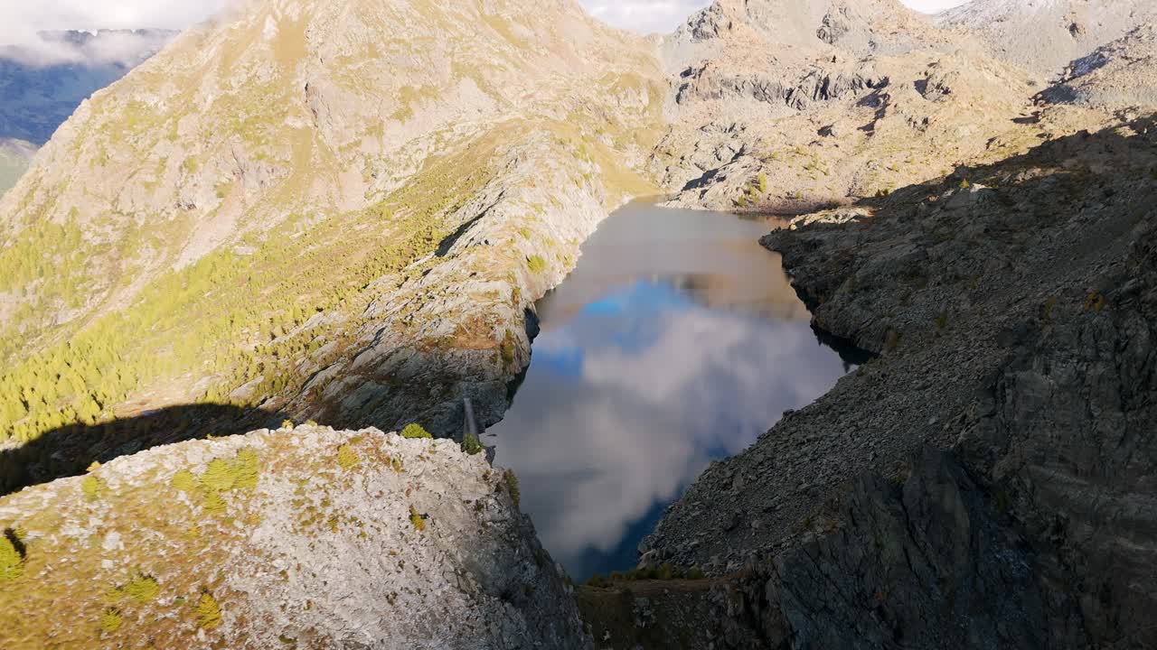 Pirola Lake in Valmalenco, Italy, calm waters reflecting cloudy sky. Aerial drone view