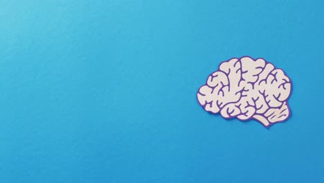 video of white and purple paper brain on blue background with copy space