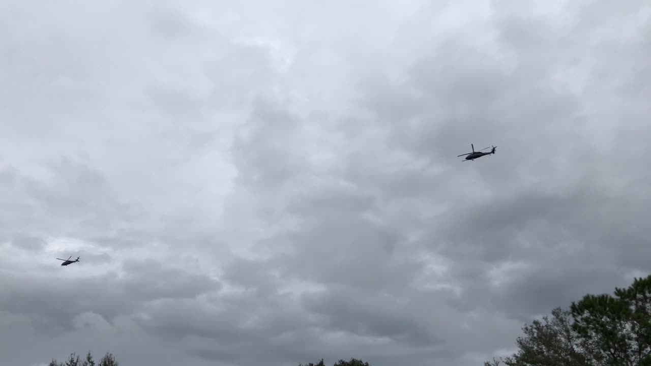 dos helicópteros que vuelan en formación por el cielo cerca del suelo en un patrón de ataque