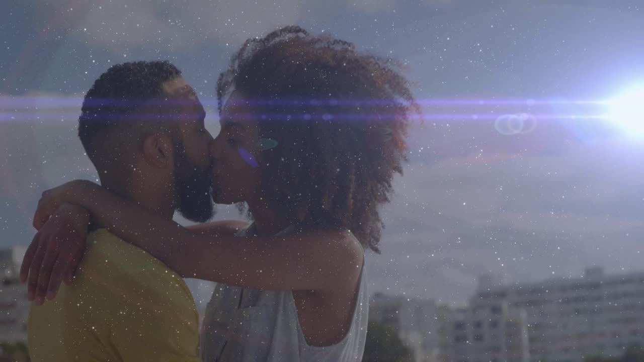 Un couple s'approche d'une terrasse et échange un tendre baiser sous un reflet lumineux de la ligne d'horizon pour illustrer un style de vie