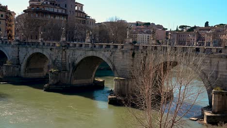 Ein-Team-Von-Ruderern,-Die-An-Einem-Sonnigen-Tag-Unter-Der-Römischen-Brücke-Sant&#39;Angelo-Vorbeifahren