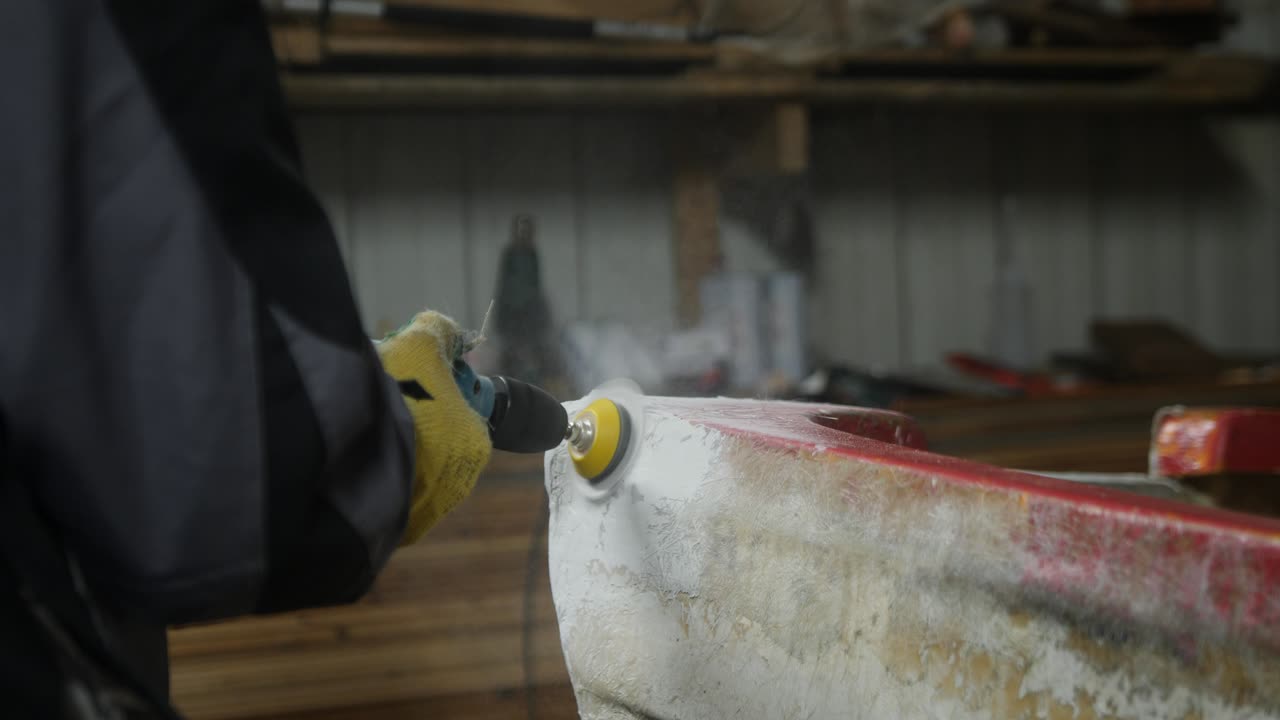 Sanding filler repair using orbital sander on fiberglass fishing boat