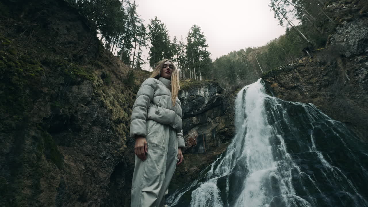 Woman Standing at a Waterfall in a Forest