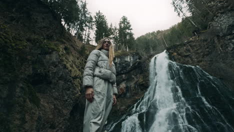 woman standing at a waterfall in a forest