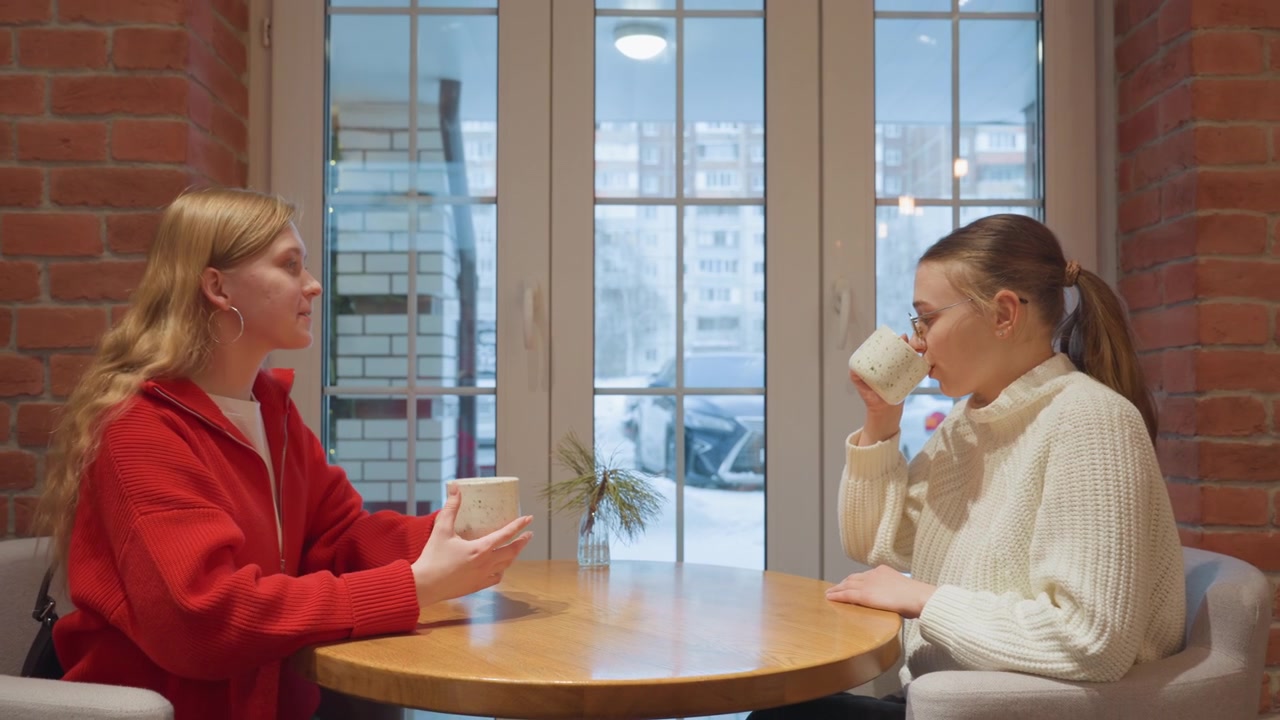 Två unga vänner dricker och pratar på ett mysigt kafé