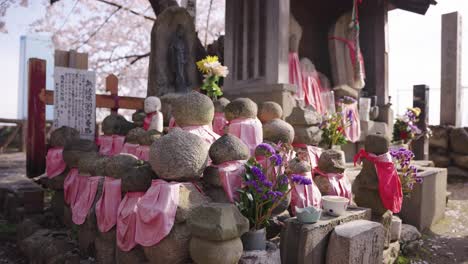 primavera en el castillo de osaka, estatuas de jizo en un pequeño santuario con árboles de sakura
