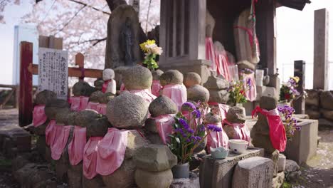 spring at osaka castle, jizo statues at small shrine with sakura trees