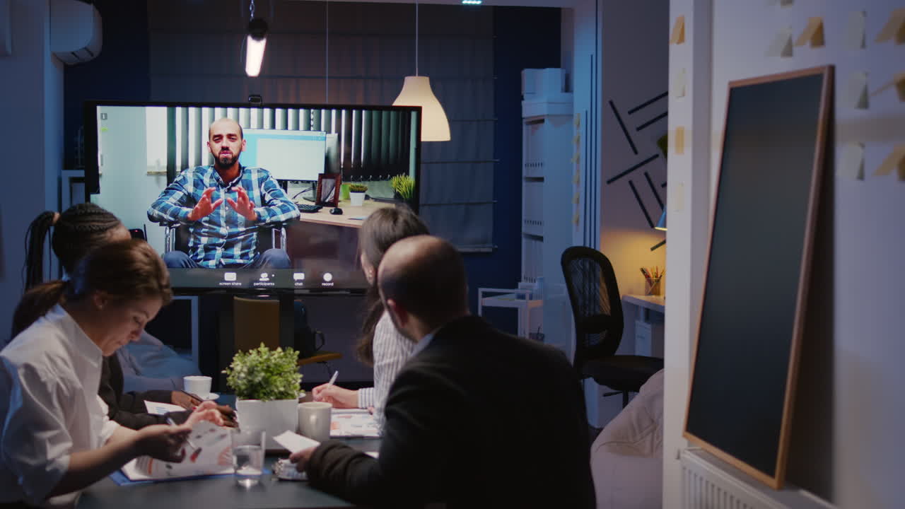 Diverse multi-ethnic businesspeople discussing with remote manager in wheelchair