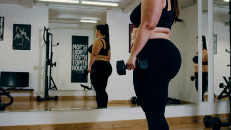 plus-size woman working out with dumbbells in gym