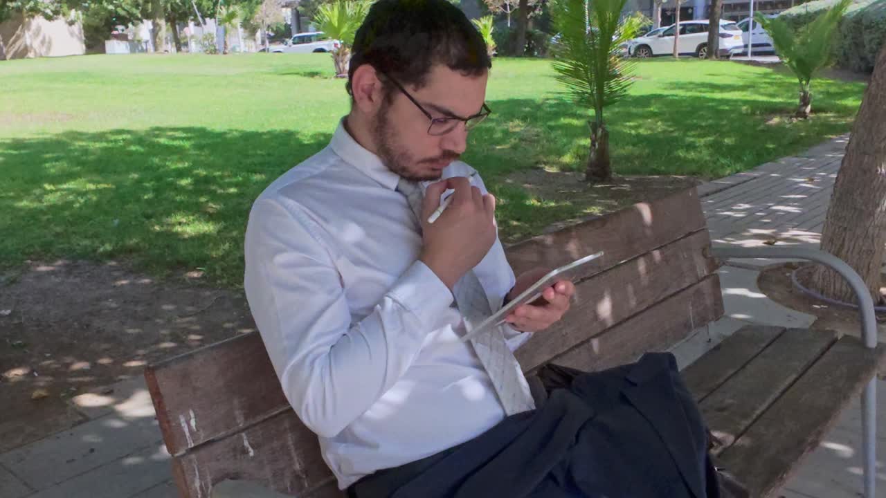 Man using tablet on park bench