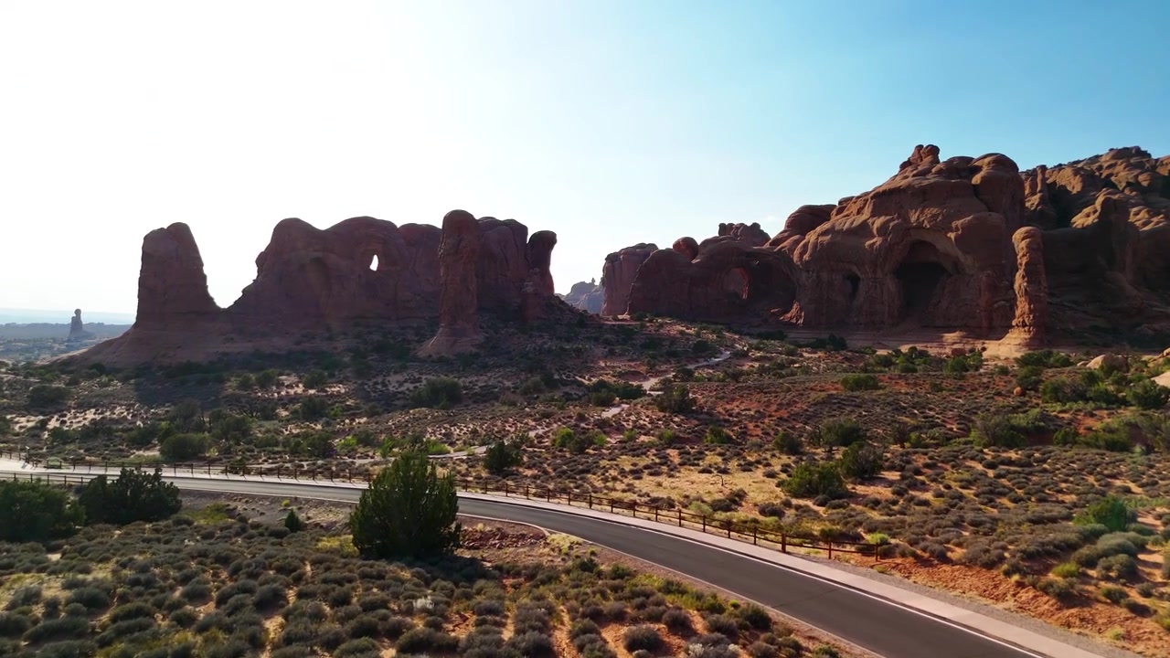 Fantastiske arkivopptak fra Arches nasjonalpark USA en lys ettermiddag. Det strålende sollyset belyser de majestetiske røde sandsteinsformasjonene og ørkenlandskapet under en klar blå himmel.