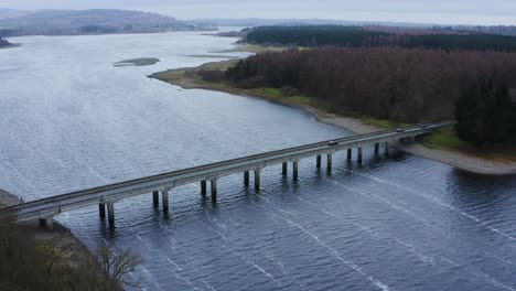 Bridging-Horizons:-Aerial-Journey-to-Baltyboys-Bridge-over-the-River-Liffey-in-the-Wicklow-Mountains,-Amidst-a-Cloudy-Evening-Drive