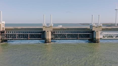 Long-aerial-shot-zooming-out-of-the-sluices-and-traffic-on-the-Eastern-Scheldt-storm-surge-barrier-in-Zeeland,-the-Netherlands,-on-a-beautiful-sunny-day