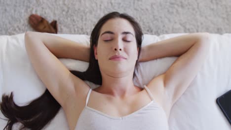 Happy-caucasian-woman-sleeping-in-bed-with-hands-under-head