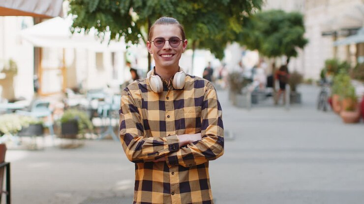 Ritratto di un uomo felice che sta in piedi di spalle, si volta sorridendo con espressione felice e guarda la fotocamera