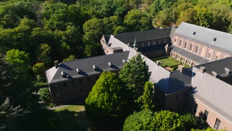 Drone-shot-of-a-monastery-surrounded-by-trees-on-a-sunny-day-in-the-summer