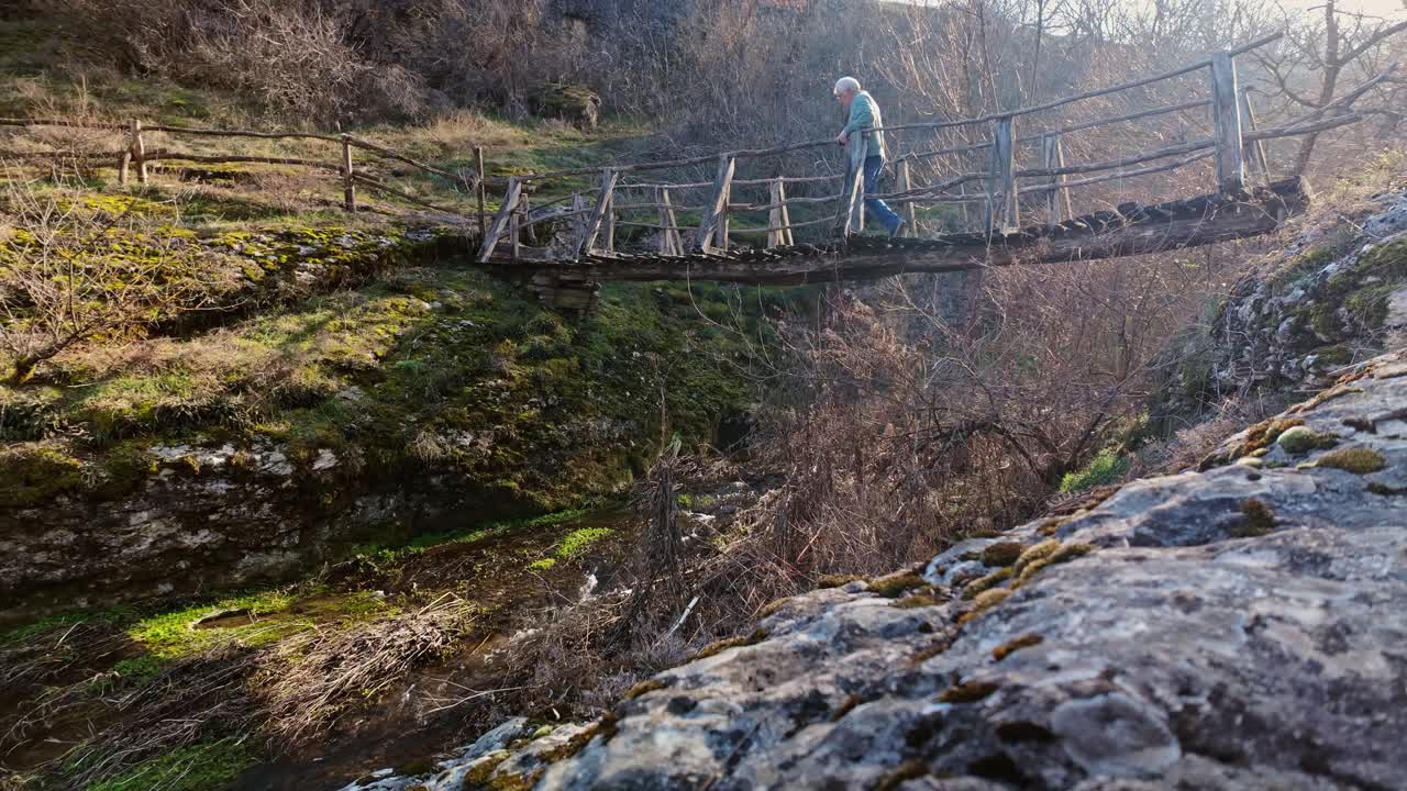 Daring man stops on rickety wood footbridge over river to take photos