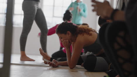 Yoga-Kurs-Mit-Schönen-Frauen,-Die-Smartphone-Technologie-Nutzen-Und-Sich-Nach-Dem-Training-Ausruhen,-Indem-Sie-SMS-Schreiben-Und-Ihren-Fitness-Lebensstil-In-Sozialen-Medien-Teilen-Und-Sich-Im-Studio-Entspannen