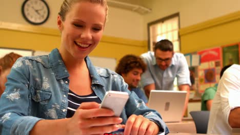 Estudiante-Rubia-Enviando-Mensajes-De-Texto-En-Su-Teléfono-En-Clase