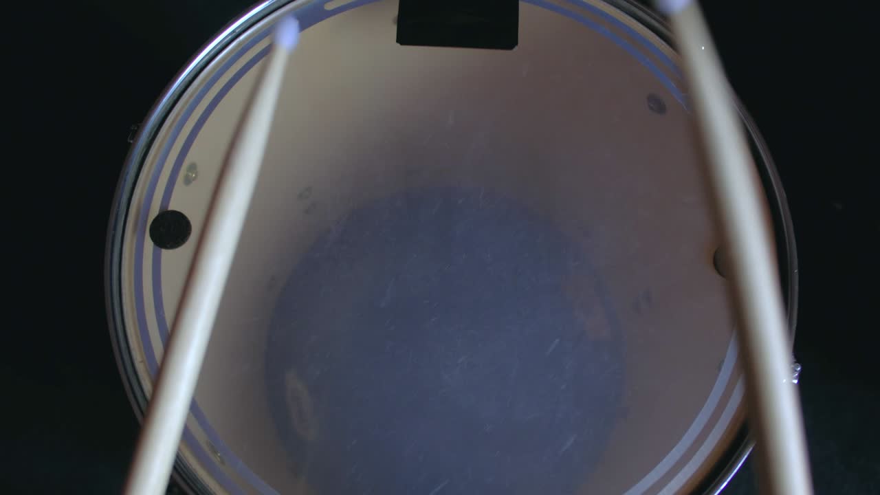 el baterista toca palos de ritmo activo en un tambor de bajo tom, entrenamiento de lección en casa