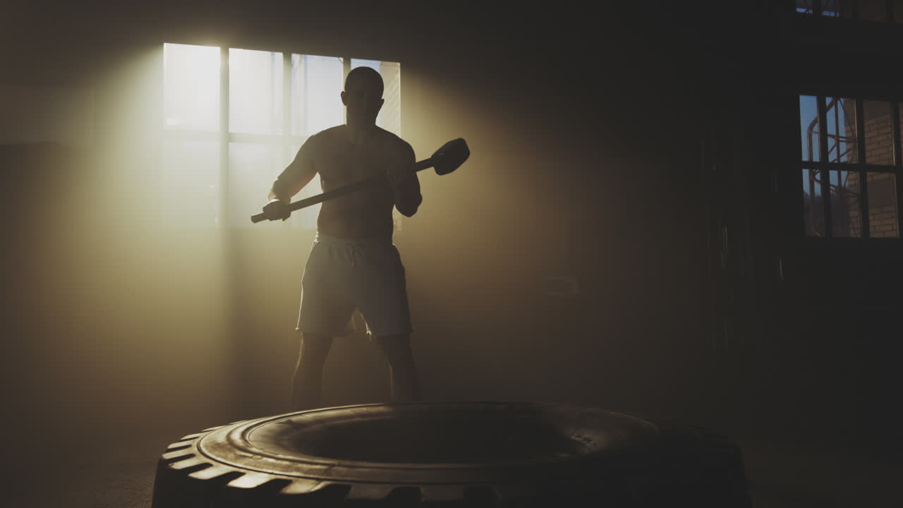 Man Hammering Tire in Gym