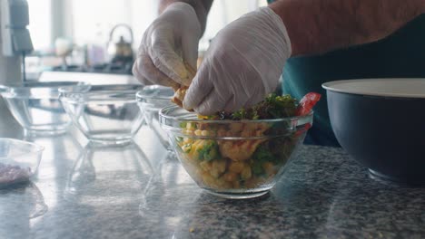 el cocinero está agregando el pollo a la ensalada