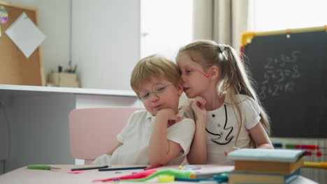 girl tells boy secret into ear and brother nods in agreement