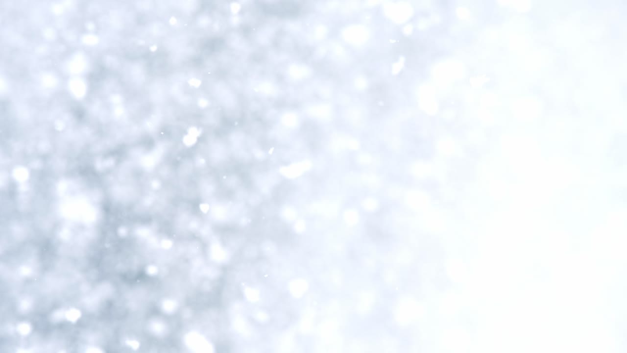 Snow particles gently move in soft abstract blur on blue background winter mood