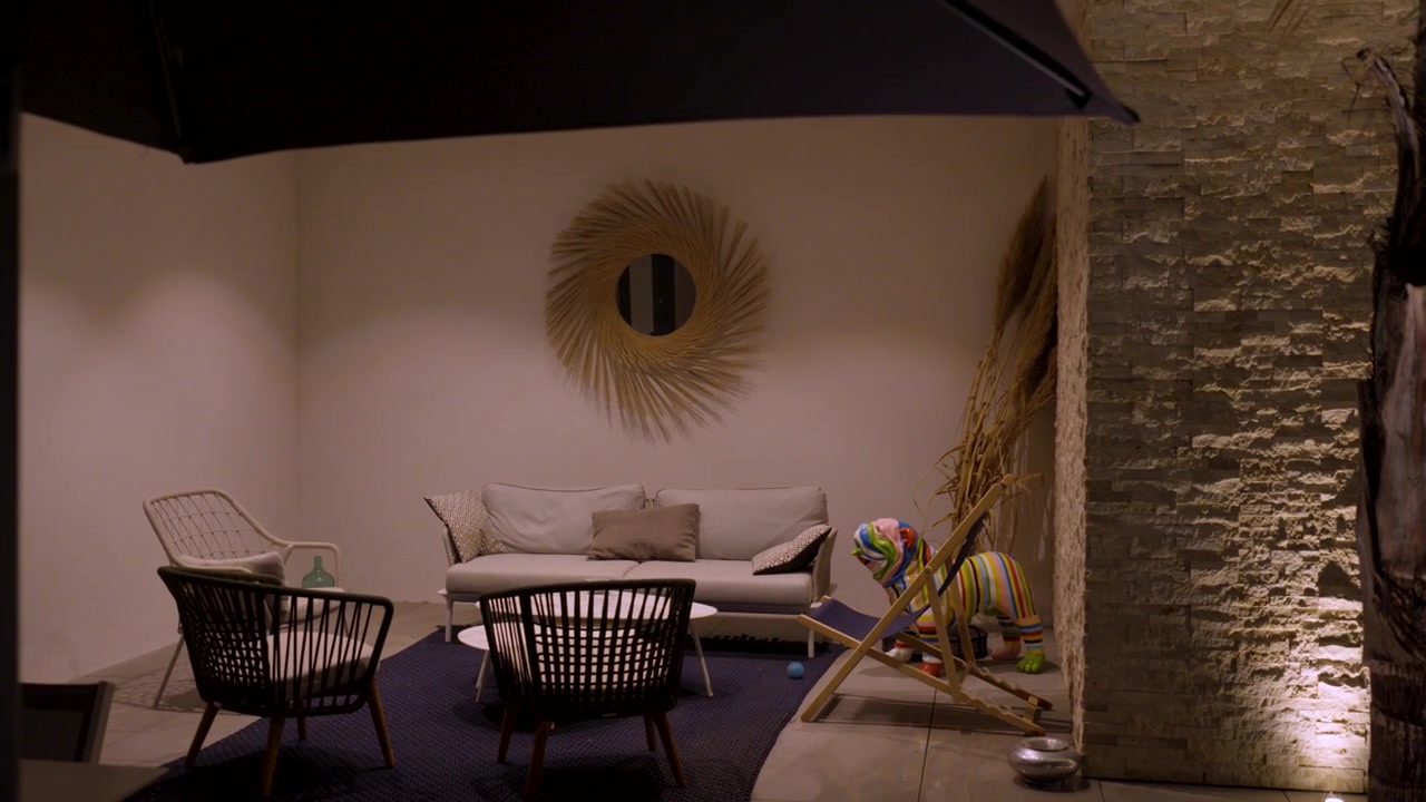 Ripresa in slow motion che rivela un'area salotto esterna con opere d'arte.
