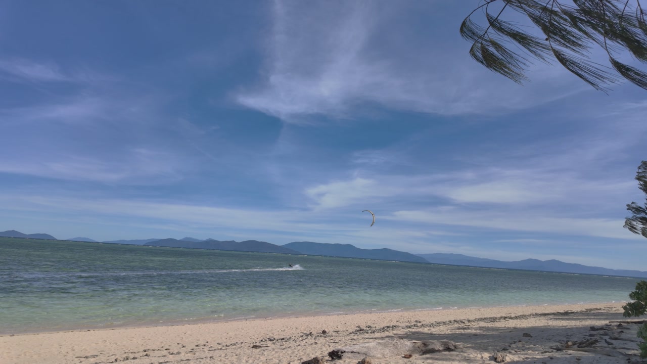 4K video footage of a sandy beach on a tropical island in Australia with a wind surfer passing by