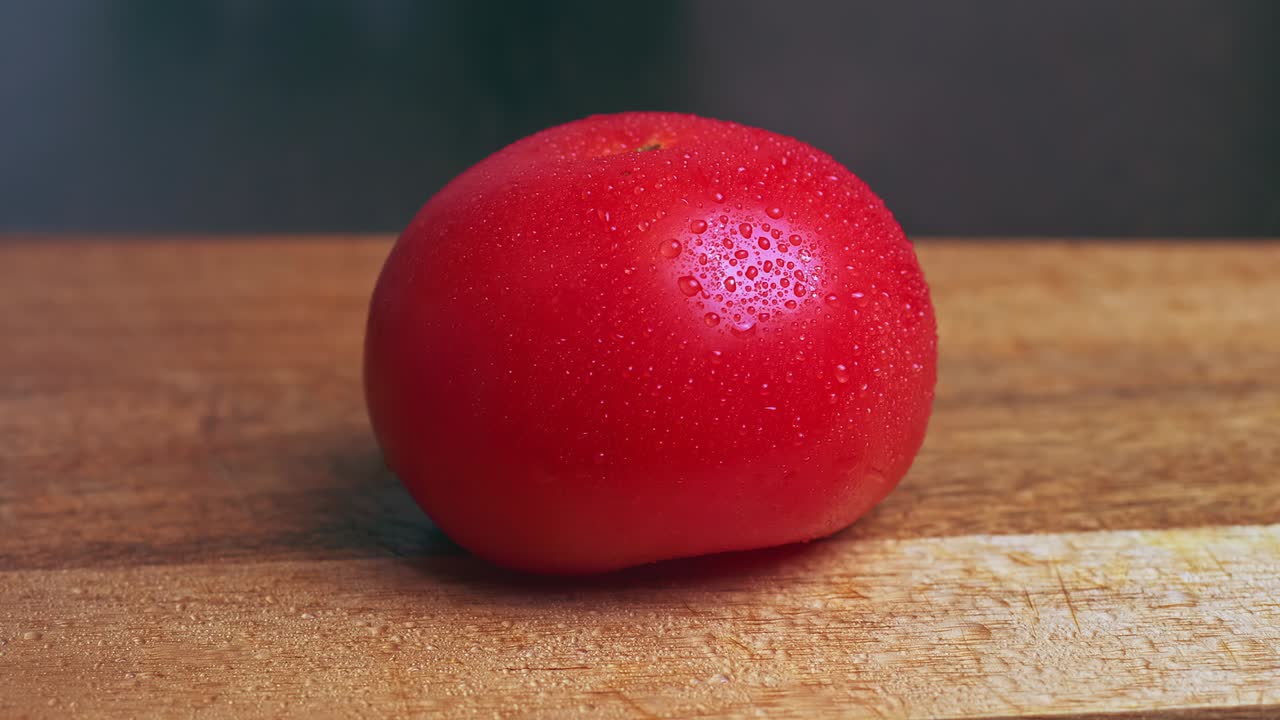 검은 바탕의 나무판에 물방울이 있는 신선한 토마토