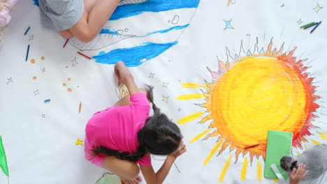 children drawing a big space picture on the floor