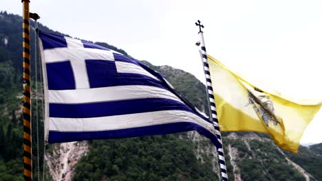 The-Greek-flag-together-with-the-Orthodox-Church-flag-with-a-green-hill-in-the-background-in-Greece