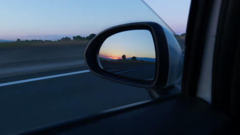 Close-up-shot-car-mirror-looking-at-vibrant-colorful-sunset-summer-day