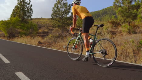 A-man-takes-his-road-bike-for-a-morning-ride-on-an-empty-road,-engaging-in-outdoor-exercise.-The-slow-motion-footage-captures-the-essence-of-extreme-sports