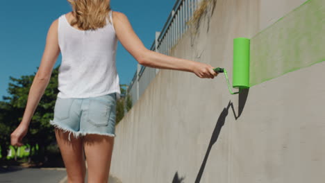 young-woman-artist-painting-wall-with-green-paint-walking-in-city-street-independent-female-enjoying-artisitic-expression-with-urban-graffiti-art-4k