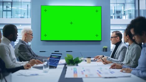 multi-ethnic office conference room meeting: diverse team of successful managers, executives talk, use green screen chroma key tv. group of businesspeople work on strategy for an e-commerce startup