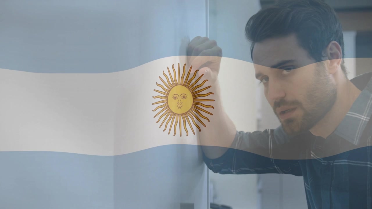 Hombre sujetando un armario, levantando la cabeza preparándose para llamar, superposición de la bandera de Argentina cruzando el encuadre, noticias.
