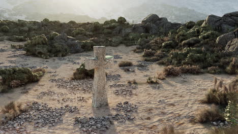 a stone cross standing in a desert landscape.