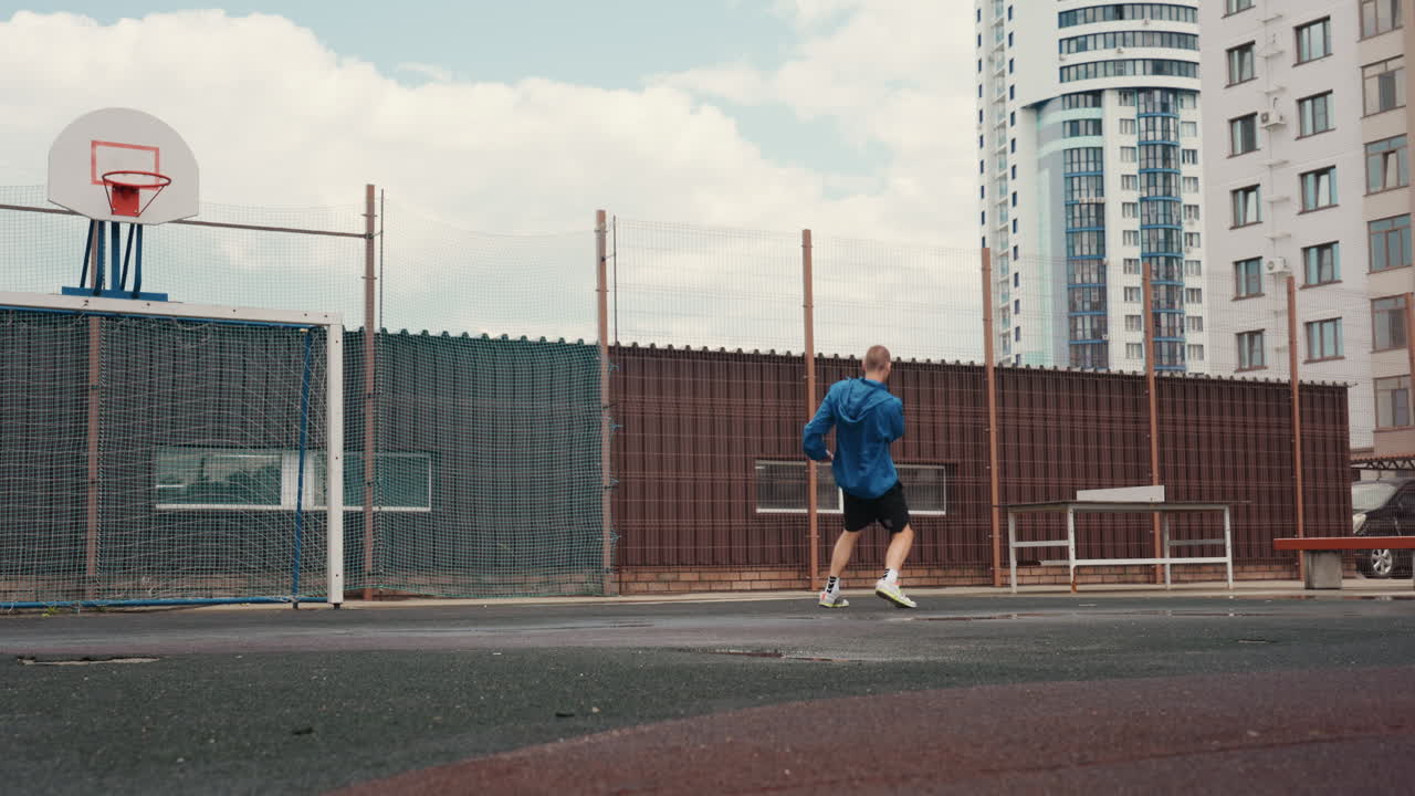 allenamento di calcio urbano all'aperto, primo piano di un campo da gioco piovoso. Primo piano di un piede che palleggia su asfalto bagnato, scarpe da ginnastica con lacci al neon e calzini bianchi. Il giocatore dribbla su un campo di quartiere recintato con un pallone da basket